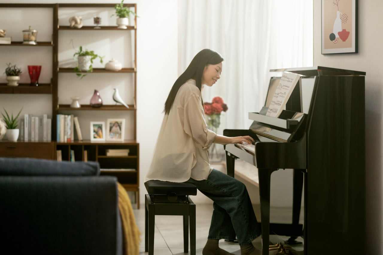 Iemand oefent thuis op een staande piano met bladmuziek op de standaard