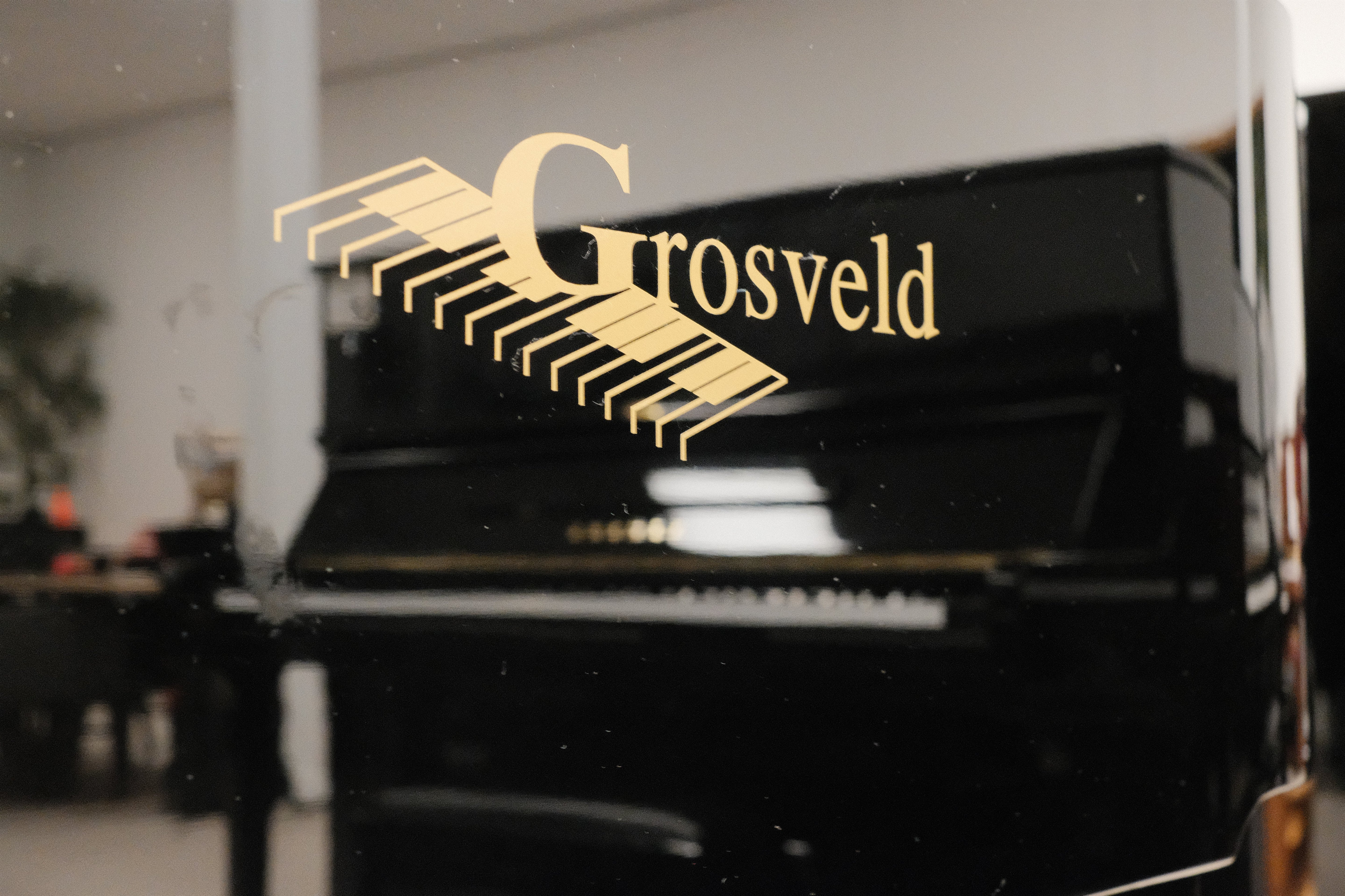 Zwarte piano met het Grosveld-logo in de showroom